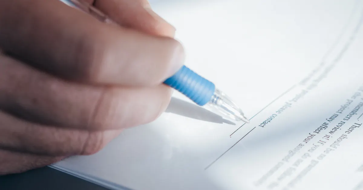Un contrat en cours de lecture et de signature, en illustration de la section « Les signaux d'alarme qui doivent mettre fin à la discussion »
