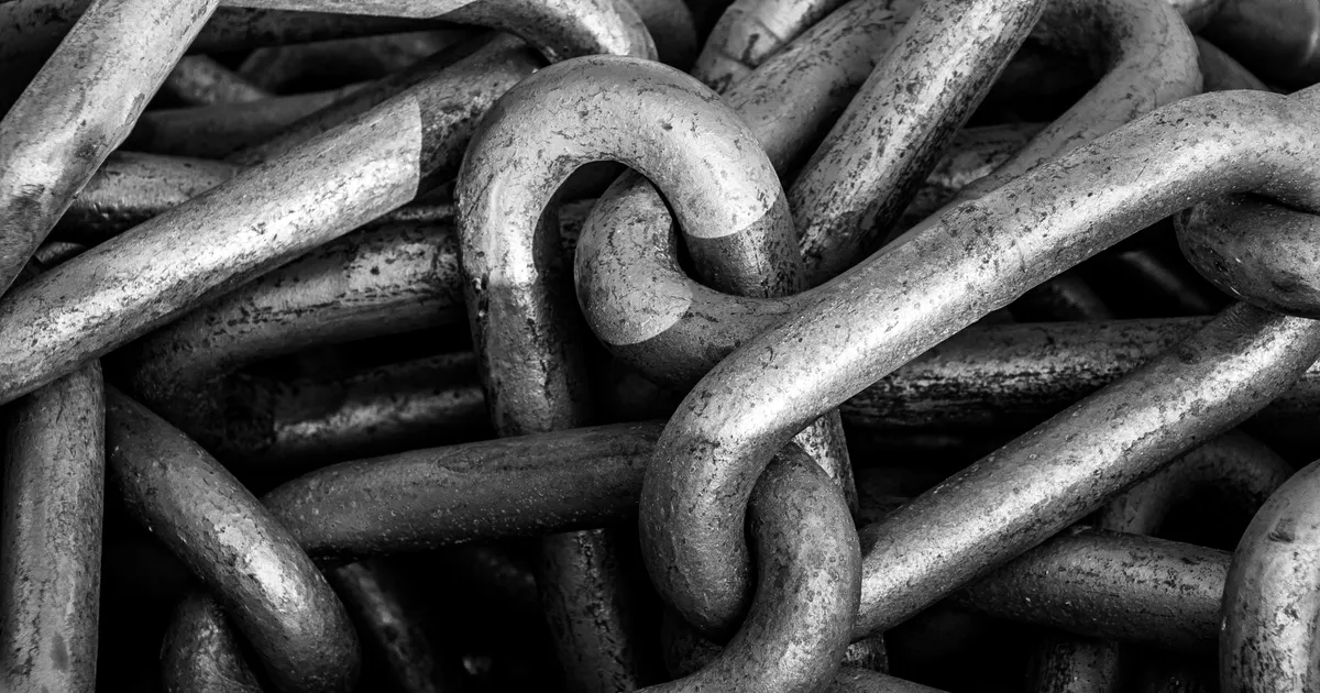 Des maillons de chaîne en métal photographiés de près, en illustration de la section « Les questions sur le processus de contenu et l'usage de l'IA »