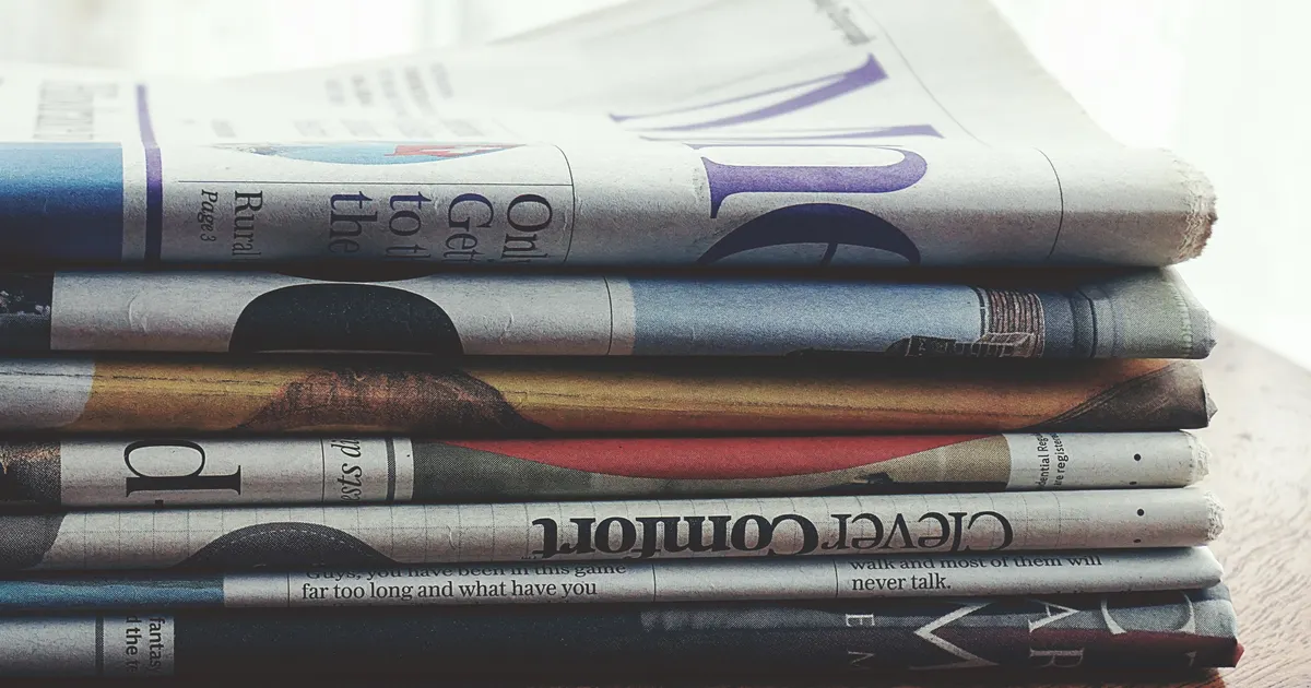 Des journaux empilés comme preuve d'une couverture presse, en illustration de la définition SEO de Mention de marque