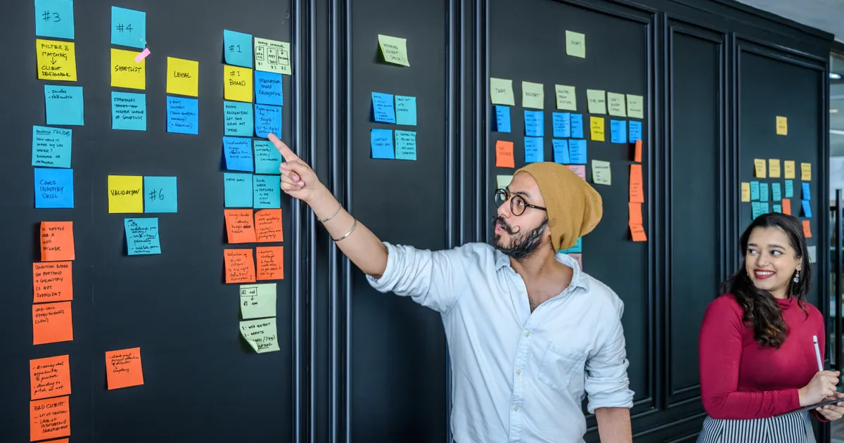 Des post-it qui couvrent un mur pendant un atelier d'idées, en illustration de la définition SEO de Maillage interne