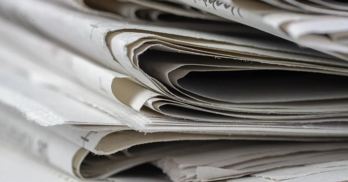 Des journaux empilés comme preuve d'une couverture presse, en illustration de la définition SEO de nofollow, sponsored, ugc