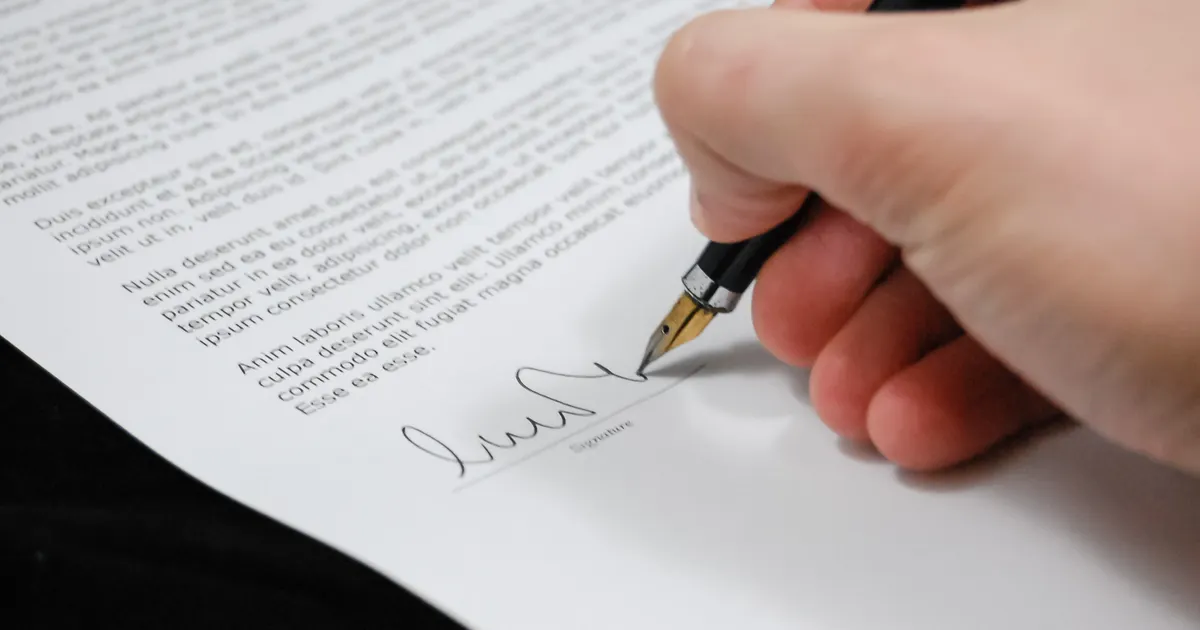 Un contrat en cours de lecture et de signature, en illustration de la définition SEO de Pénalité (action manuelle)