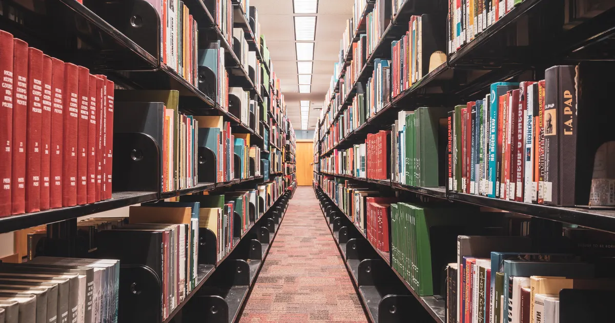 Des rangées d'ouvrages de référence sur les étagères d'une bibliothèque, en illustration de la définition SEO de SEA (référencement payant)