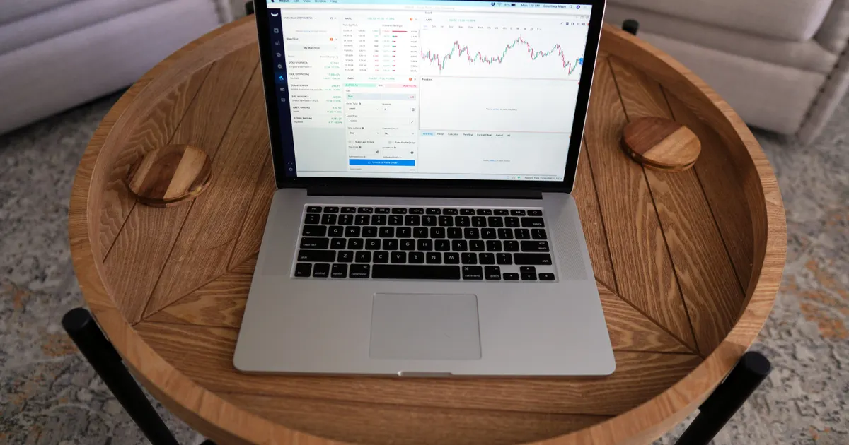 Close-up of a laptop displaying trading charts on a stylish wooden table, ideal for…, illustrating the Analytics software compared on Trust Agency